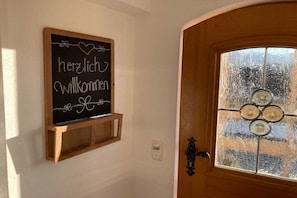 A wooden door with a frosted glass window and a blackboard with 'herzlich willkommen' written on it. - Holiday apartment with 2 bedrooms (Bad Bayersoien)