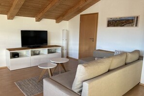 Un salon moderne avec un canapé, un téléviseur et une petite table.