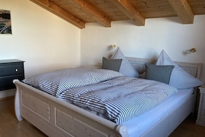 Een slaapkamer met een bed, nachtkastjes en een houten plafond.