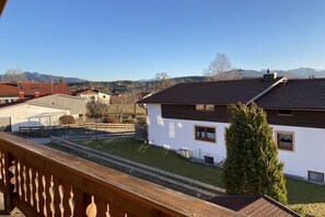 Un quartier résidentiel avec une maison blanche, une terrasse en bois et une vue dégagée sur les montagnes lointaines.