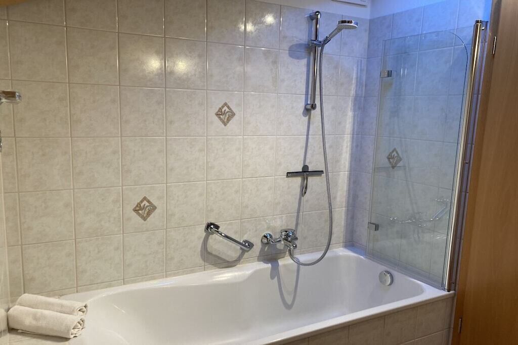 A bathroom with a bathtub, shower, and glass-enclosed shower area.