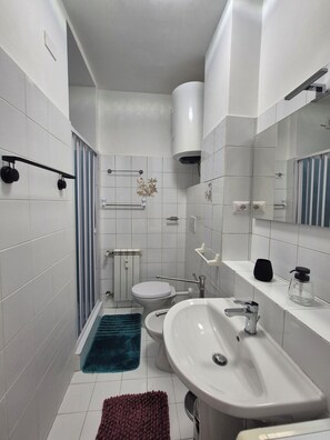 A modern bathroom with a toilet, sink, and shower area. - Vrbo Property (Roma)