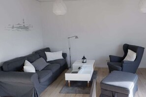 A modern living room with a grey sofa, a white coffee table, and a grey armchair. - Holiday home in Burhave with swimming pool (Burhave)