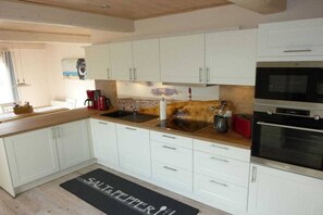 A modern kitchen with white cabinets, a wooden countertop, and a black oven. - Holiday apartment with 2 bedrooms (Kappeln)