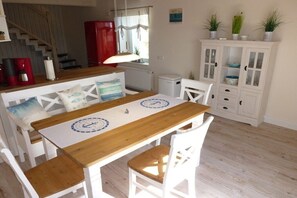 A dining area with a wooden table and white chairs, a red cabinet, and a white cabinet with glass doors. - Holiday apartment with 2 bedrooms (Kappeln)