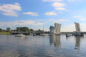 A river with a bridge, boats, and a small building with a green roof. - Holiday apartment with 2 bedrooms (Kappeln)
