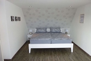 A bedroom with a white bed, grey bedding, and a patterned wallpaper. - Holiday apartment with 2 bedrooms (Kappeln)