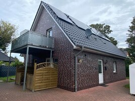 En envåningsbyggnad i tegel med ett sluttande tak, en balkong och en grind vid ingången.