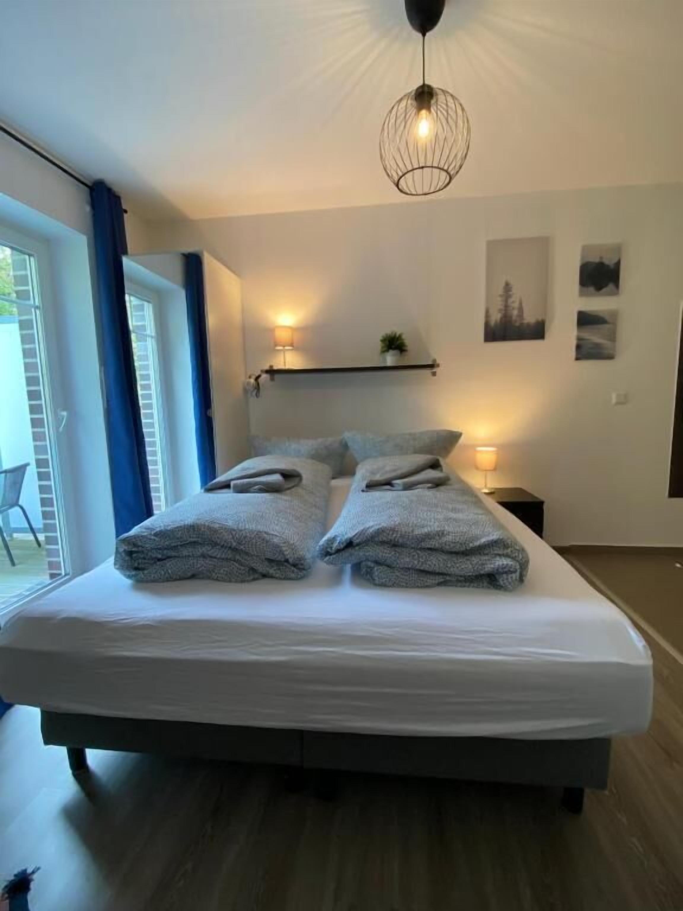 Ein Schlafzimmer mit einem Bett, Nachttischlampen und Blick ins Freie.