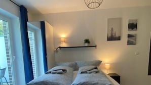 Quarto com cama, abajures e vista para o exterior.