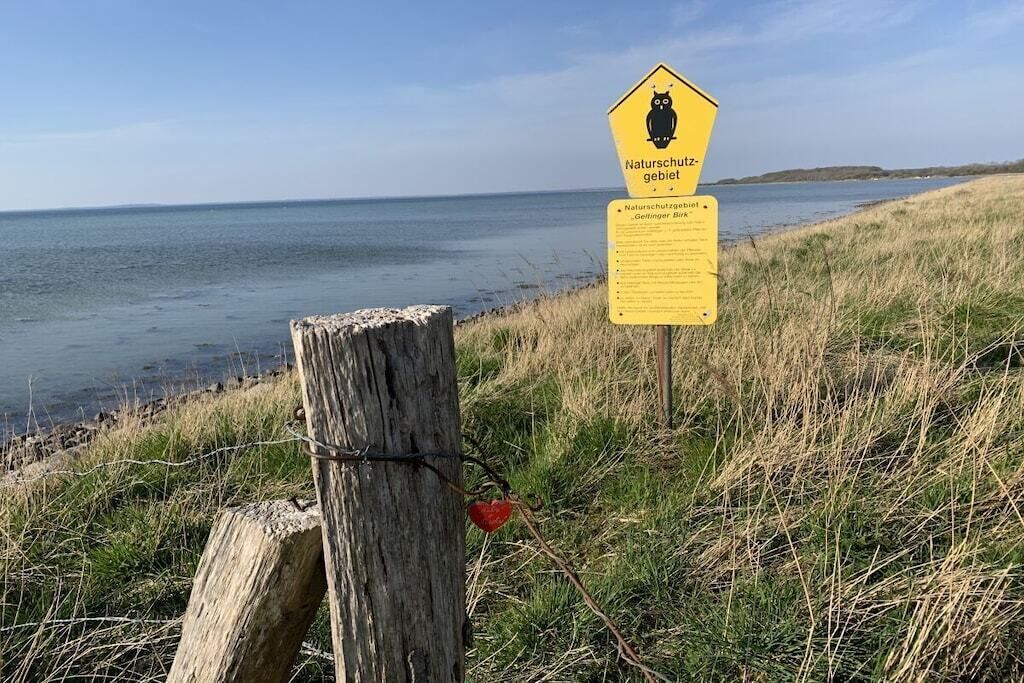 Un panneau indiquant une zone naturelle protégée, situé le long d’un sentier côtier.