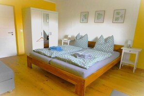 Een slaapkamer met een bed, kast, nachtkastjes en een deur.