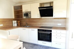 A compact kitchen with white cabinets, a built-in oven, a microwave, and a coffee maker. - Holiday apartment with 1 bedroom (Jabel OT Loppin)