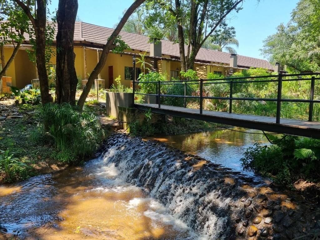 Een kleine waterval, een brug en een gebouw met een pannendak.
