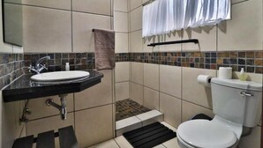 Un baño con lavamanos, inodoro y zona de ducha.