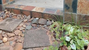 Un espacio patio al aire libre con una mesa, sillas, un camino de piedra y una puerta.