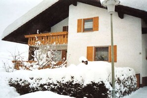 Ein zweigeschossiges Gebäude mit Balkon, Holzh shutters und einem mit Schnee bedeckten Dach.