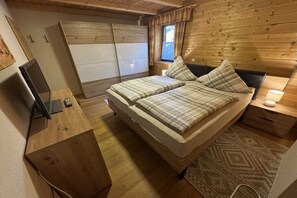 Een compacte slaapkamer met een bed, nachtkastje en bureau met een computer.