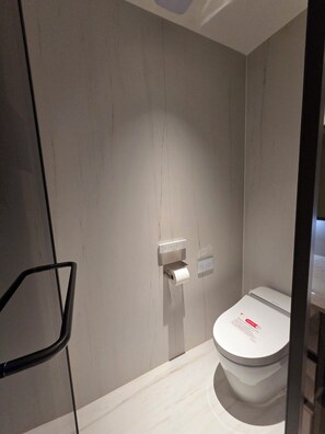 A modern bathroom with a toilet, a paper towel dispenser, and a black chair. - A brand-new, luxury high-end officetel in Seocho-dong (Seoul)