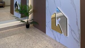 A reception desk with a marble finish, a plant, and a modern light fixture. - Komunna luxe (Batumi)
