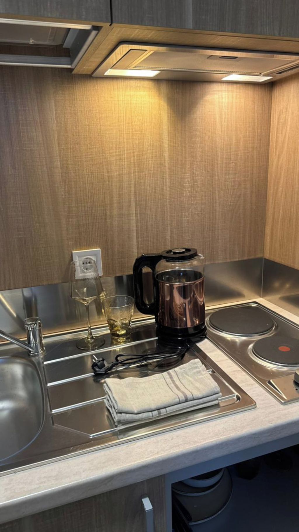 Una cocina moderna con una cafetera, una copa de vino y una toalla sobre la encimera.