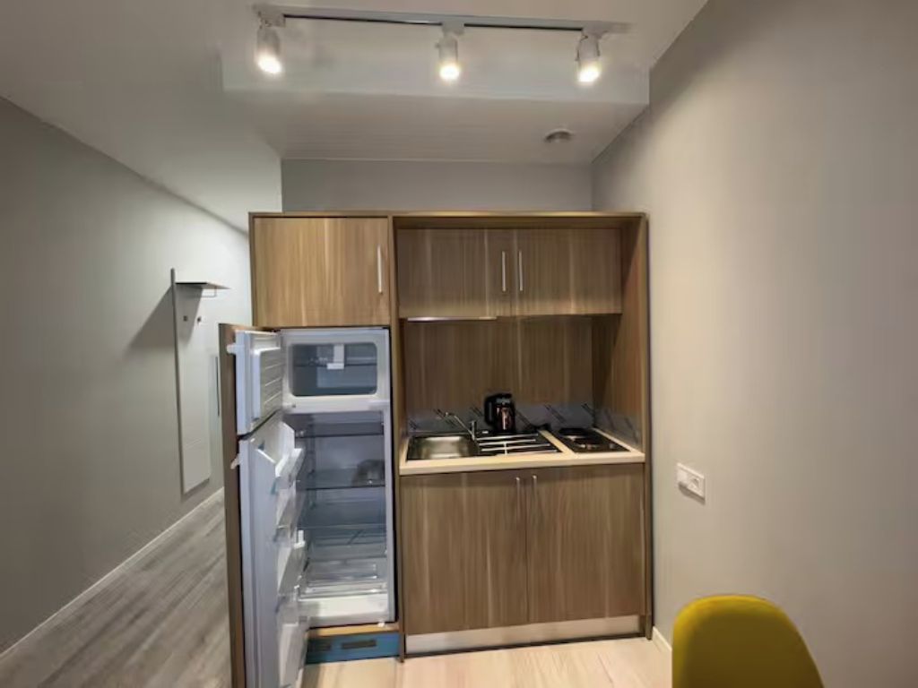 Una cocina compacta con electrodomésticos integrados, armarios de madera y una pequeña encimera.