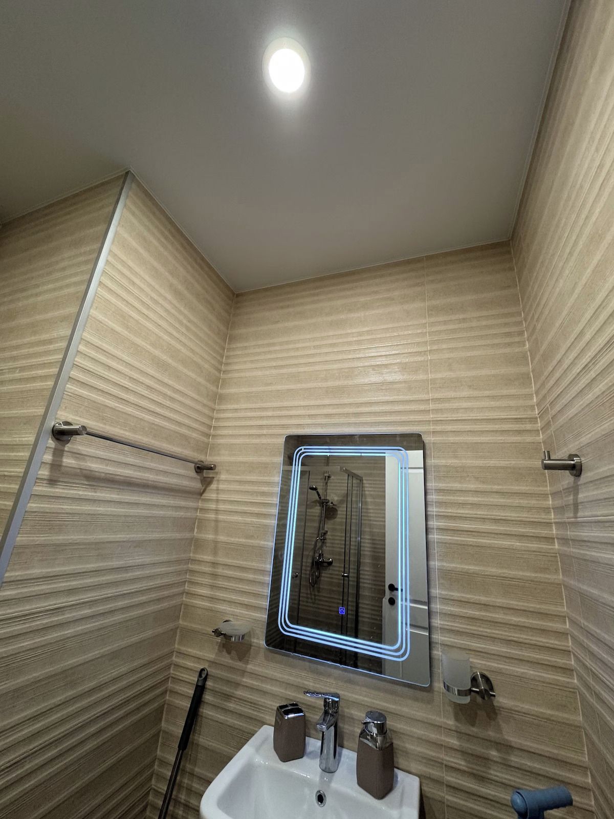 Ein Badezimmer mit Dusche, einem Waschbecken mit zwei Becken und einem Spiegel mit Beleuchtung.