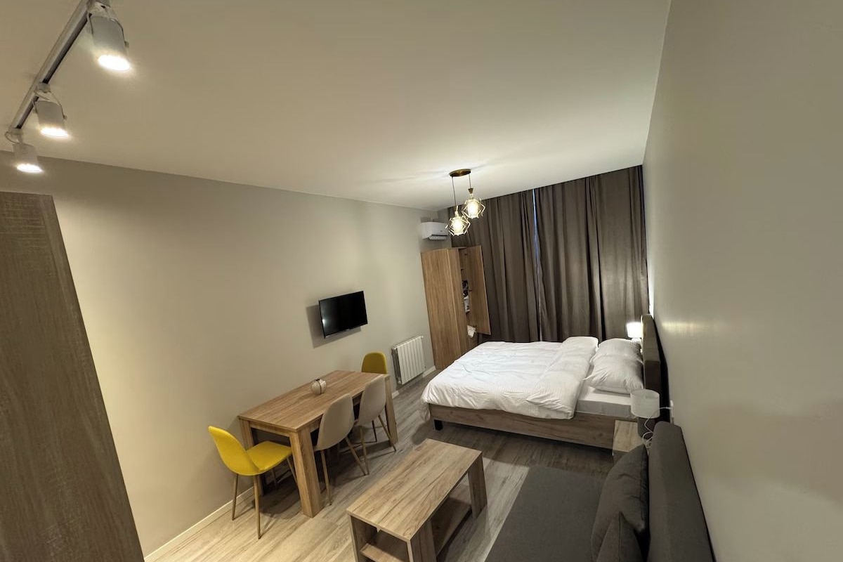 Ein modernes Hotelzimmer mit Bett, Schreibtisch, Sessel, Fernseher und einer Couch.