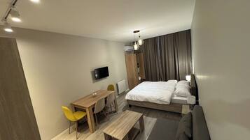 Una habitación de hotel moderna con cama, escritorio, silla, televisor y sofá.