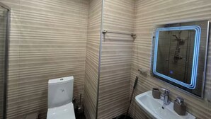 A bathroom with a toilet, a sink, and a shower area. - Komunna luxe (Batumi)