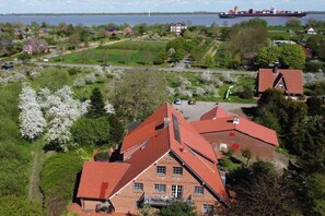 A residential area with houses, a large body of water, and a cargo ship in the distance. - Holiday apartment with 2 bedrooms (Elbinsel Krautsand)