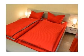 Un lit double avec une literie rouge et deux lampes de chevet.