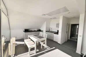 A compact kitchen with a dining area, white cabinetry, and a small island. - Holiday apartment with 1 bedroom (Ückeritz)