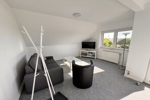 A modern living room with a sofa, coffee table, and a black trash bin. - Holiday apartment with 1 bedroom (Ückeritz)