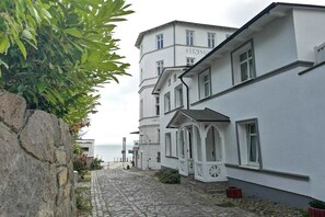 A white building with a stone wall and a cobblestone path leading to the sea. - "BALTIC SAND" with balcony (Sassnitz)