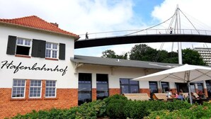 A building with a sign reading 'Hafenbahnhof' and a pedestrian bridge above. - "BALTIC SAND" with balcony (Sassnitz)