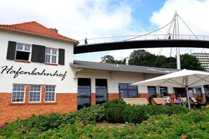 Een gebouw met een bord waarop 'Hafenbahnhof' staat en een voetgangersbrug erboven.