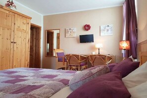Een hotelkamer met een bed, een bureau met stoelen, een televisie en een spiegel.