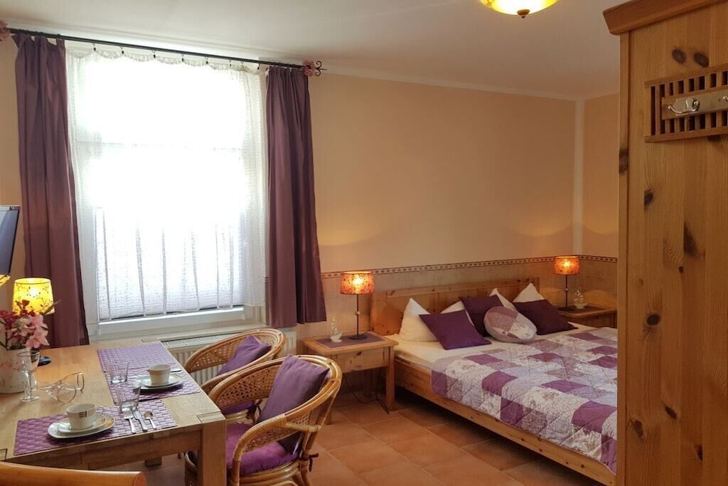 A bedroom with a bed, bedside tables, a desk with a chair, and a window with curtains.