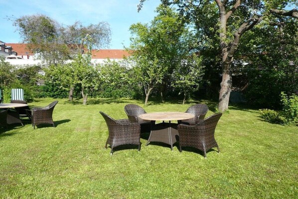 Een terras met rieten meubilair en een ronde tafel.