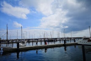 A marina with multiple boats docked, a pedestrian walkway, and a cloudy sky. - "BALTIC SAND" with balcony (Sassnitz)