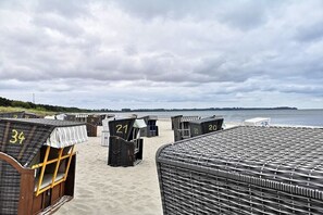 Een rij genummerde strandhutten aan het strand, met uitzicht op zee.