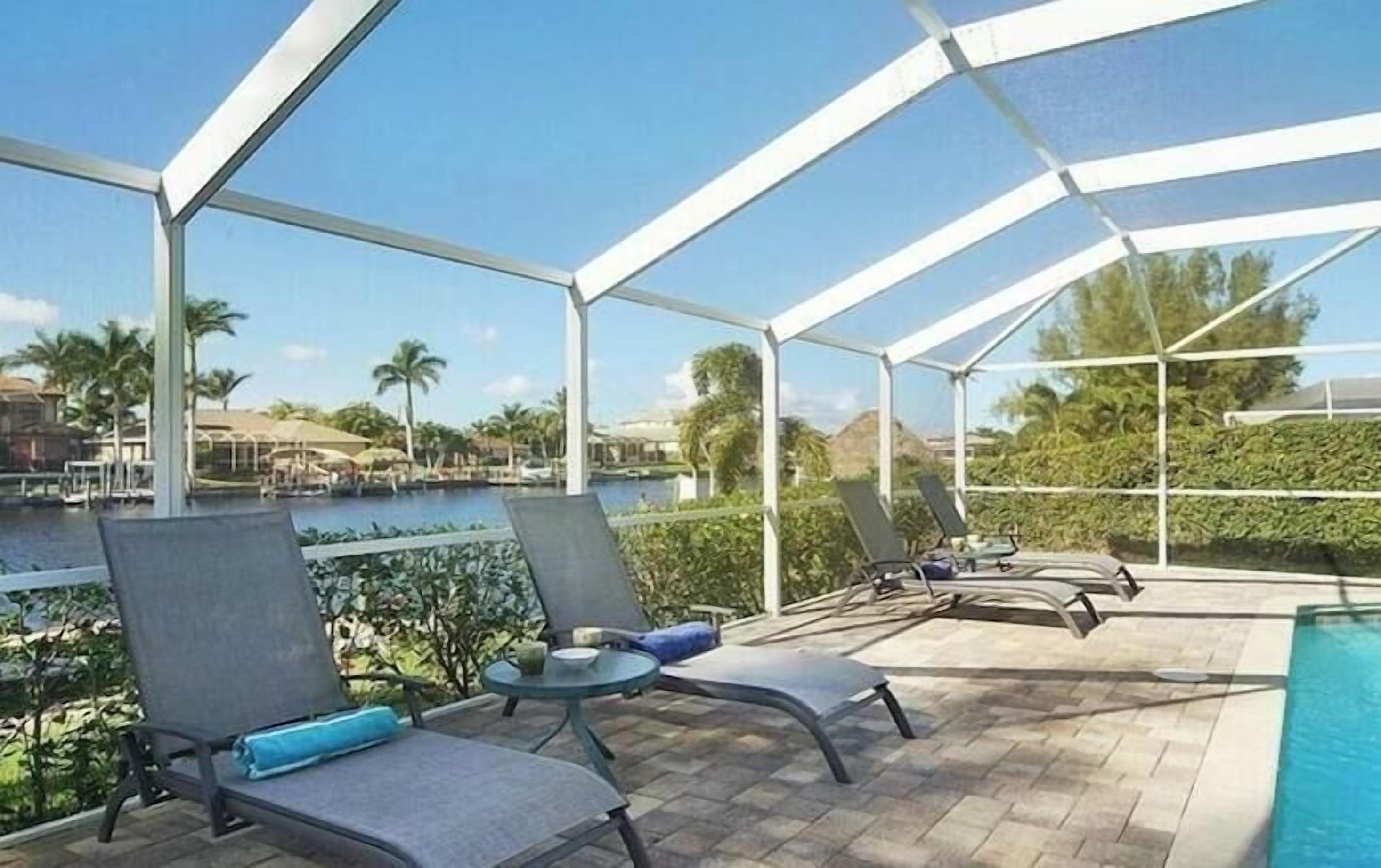 Un espacio exterior cubierto con sillones de descanso y una piscina.