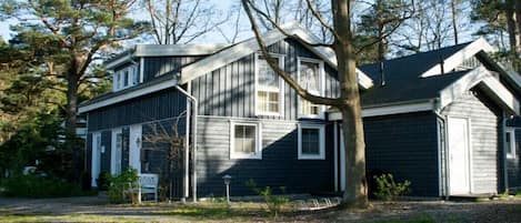A two-story house with a sloped roof, surrounded by trees.