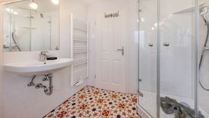 Une salle de bain avec une douche à parois de verre, un lavabo blanc et un carrelage décoratif.