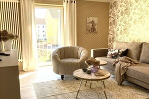 Een woonkamer met een bank, fauteuil en een ronde tafel.