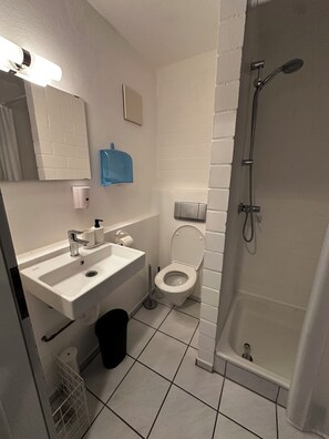 A bathroom with a white sink, toilet, and shower. - Vrbo Property (Aidlingen)