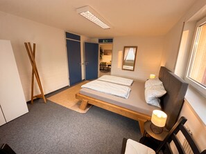 A bedroom with a bed, bedside table, lamp, and a window. - Vrbo Property (Aidlingen)