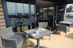 An outdoor dining area with wicker furniture and a table set for two. - LaFe Flensburg Fjord (Egernsund)