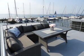 A rooftop lounge area with a sofa and table, overlooking a marina with boats. - LaFe Flensburg Fjord (Egernsund)